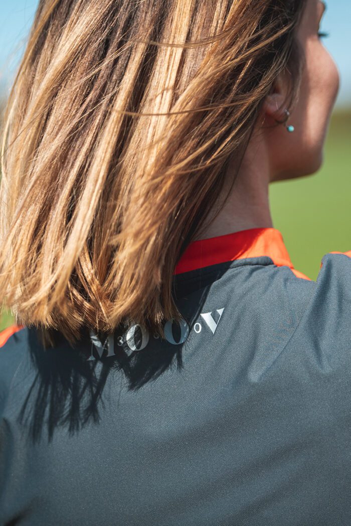 Detailfoto van een vrouw in een veld die eco-verantwoorde sportkleding draagt Grijs - Oranje